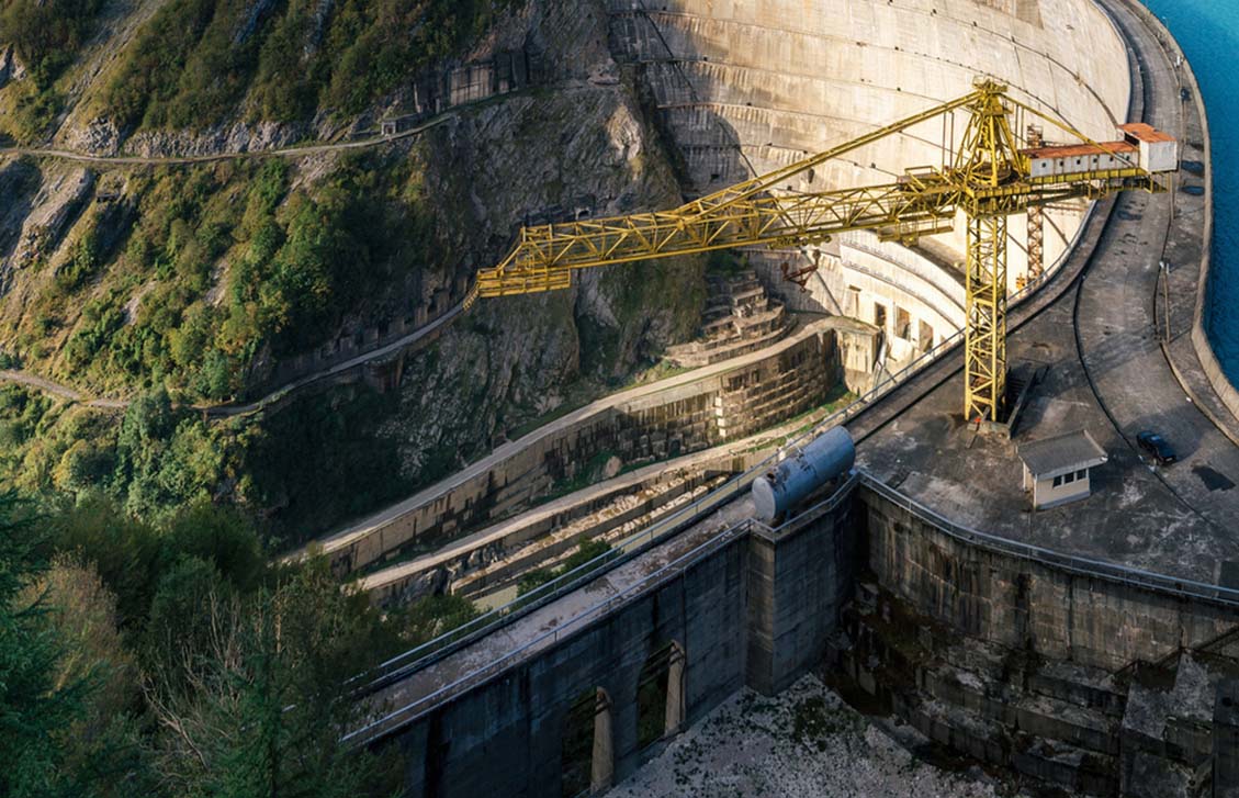 Crane operating at a construction site next to a dam